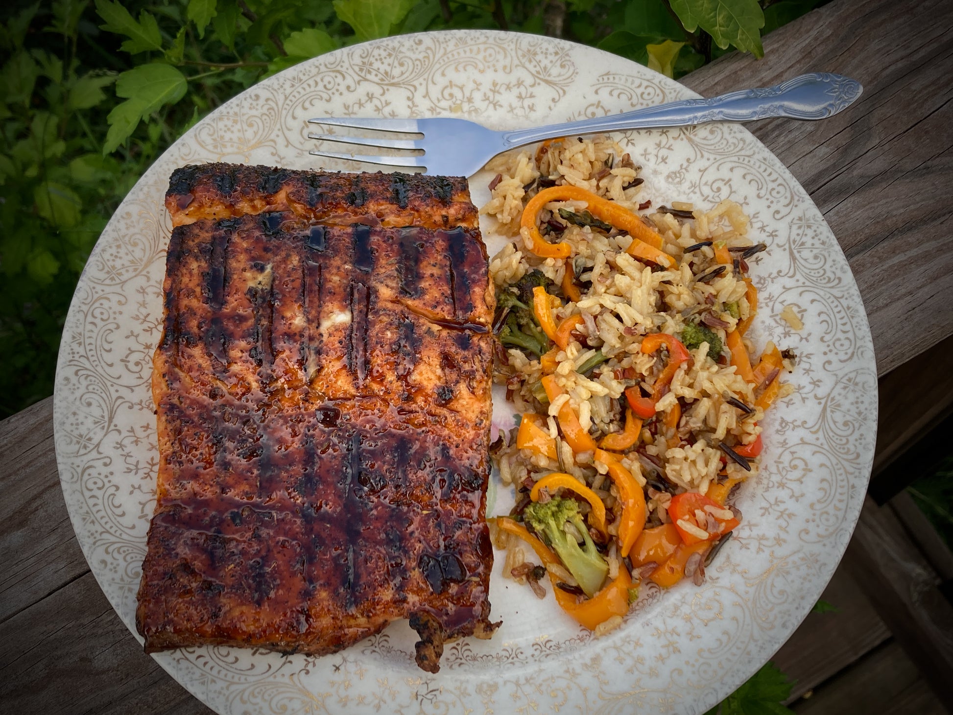 Grilled fish fillet on a plate with rice and vegetables outdoors